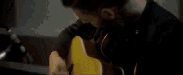 a man is playing an acoustic guitar in front of a microphone .