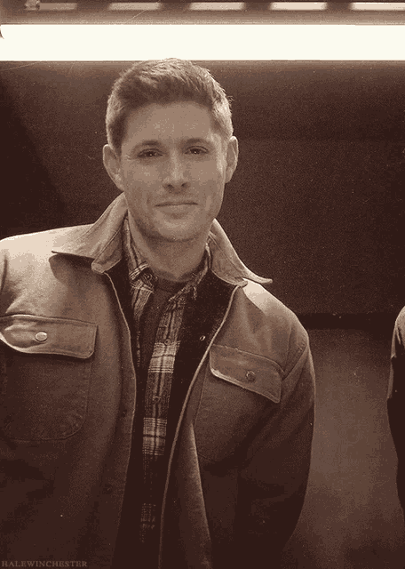 a man wearing a plaid shirt and a brown jacket has halfwinchester written on the bottom right
