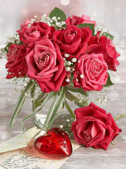 a bouquet of red roses in a vase next to a heart