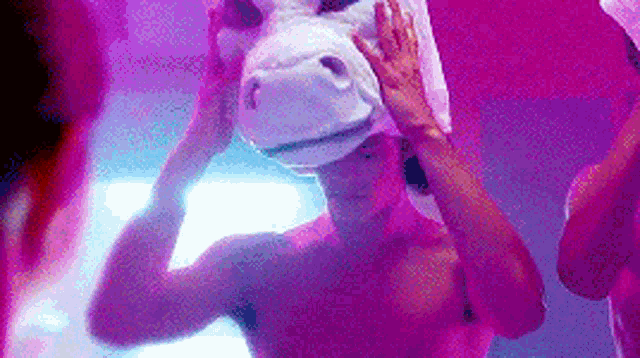 a man without a shirt is wearing a unicorn mask .