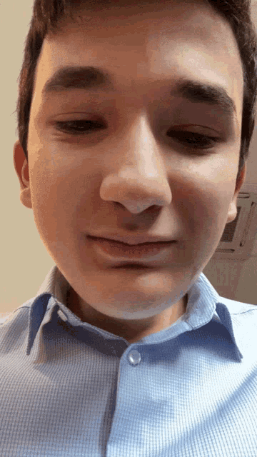 a close up of a young man 's face with a blue shirt on
