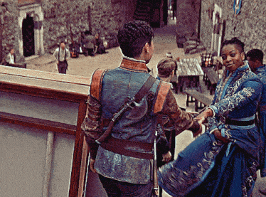 a woman in a blue dress holds the hand of a man in a blue jacket