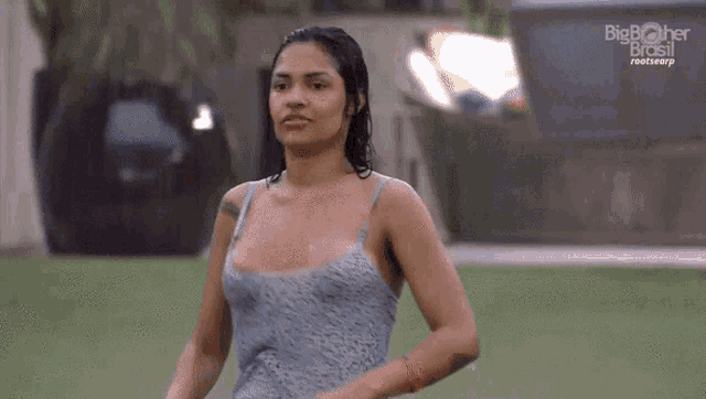 a woman in a blue tank top is standing in the rain