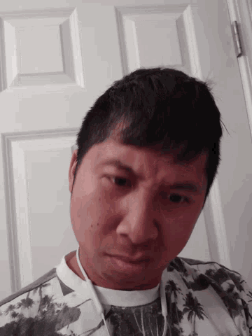 a man with a floral shirt is looking down at the camera