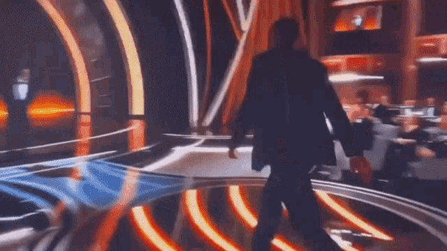a man in a suit walks on a stage