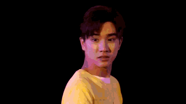 a young man wearing a yellow shirt and a white shirt is making a funny face .