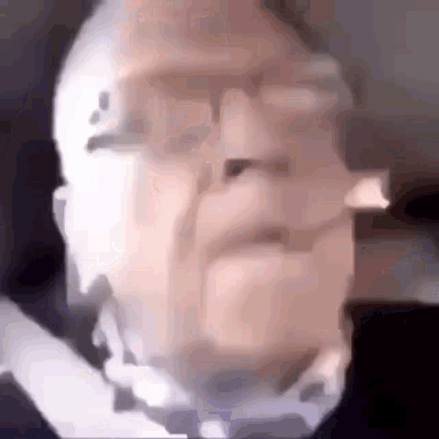 a blurry picture of a man with glasses and a bow tie .