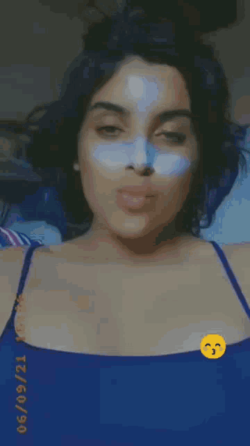 a woman wearing a blue tank top with a smiley face on her chest