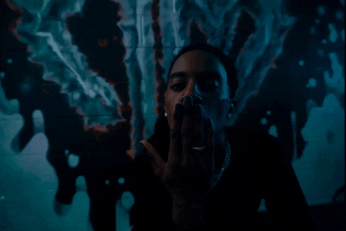 a man with a nose ring is smoking a cigarette in front of a painting