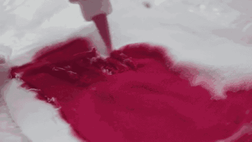 a person is pouring red liquid into a white container .