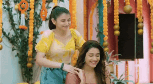 two women are standing next to each other in a room with flowers .