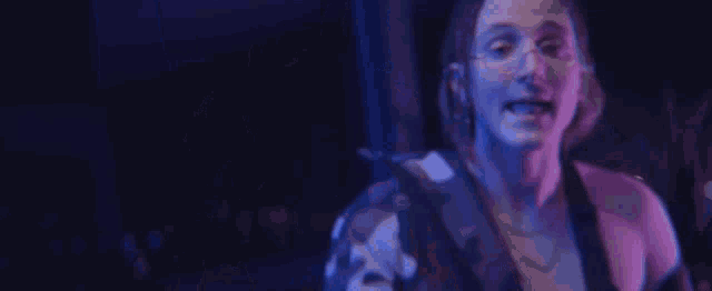 a woman is playing a video game in a dark room with a controller .