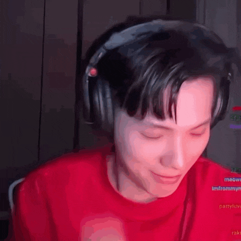 a man wearing headphones and a red shirt is sitting in a dark room .
