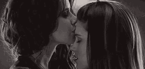 a black and white photo of two women kissing .
