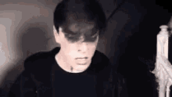 a close up of a person 's face in a dark room with a skeleton in the background .