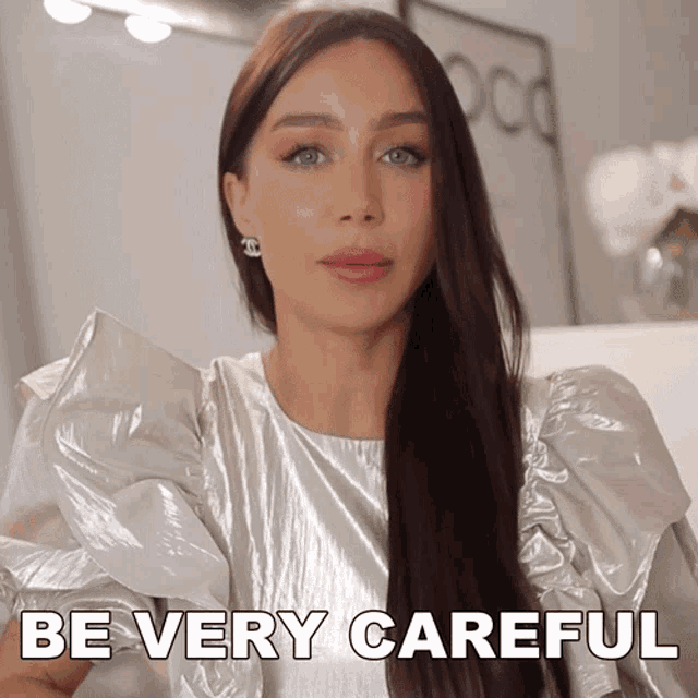 a woman says be very careful while wearing a silver top and earrings