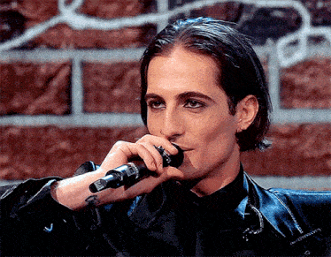 a man with a tattoo on his wrist holds a microphone