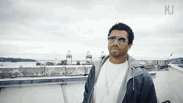 a man wearing sunglasses stands on a rooftop with the letters m.i. on the bottom