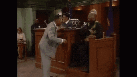 a man in a suit is dancing in a courtroom while people watch .