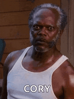 a man with a beard is wearing a white tank top and says cory .