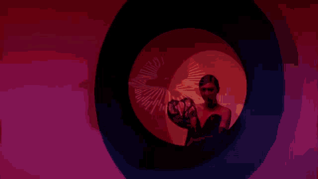 a woman is standing in a circle with a red light behind her