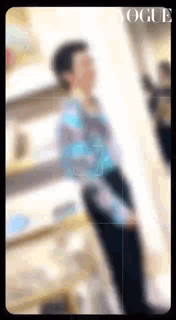 a blurry photo of a woman sitting in front of a mirror with the word vogue on the bottom