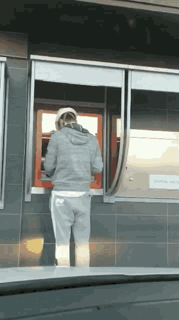 a person standing in front of a drive thru window with a sign that says caution smoking