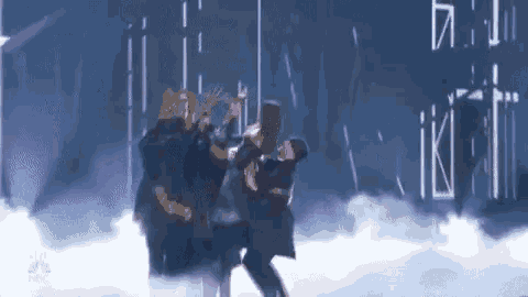 a group of people are dancing on a stage in a dark room .