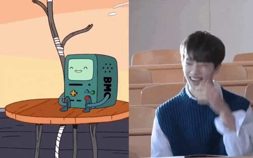 a cartoon character named bmo sits on a table next to a man in a classroom