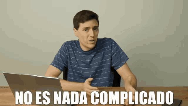 a man sitting at a desk with a laptop and the words no es nada complicado written on the screen