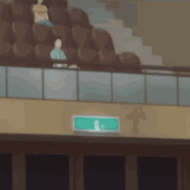 a blurry picture of people sitting in a stadium with a green exit sign