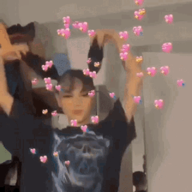 a girl is making a heart shape with her hands in front of a mirror .