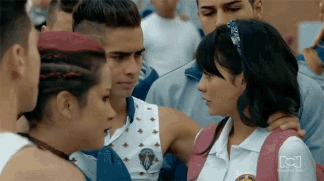a group of people are standing next to each other and one of them has a pink backpack on .