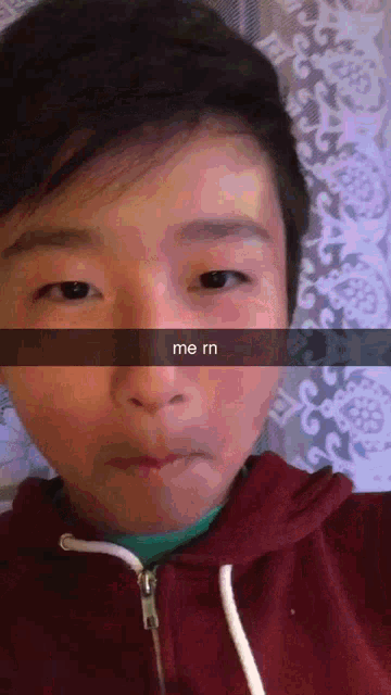 a young boy taking a selfie with the words me rn written on his face