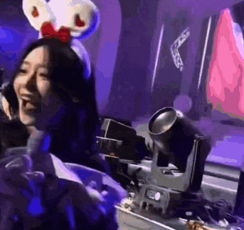 a woman wearing a mickey mouse headband is sitting in front of a microphone .