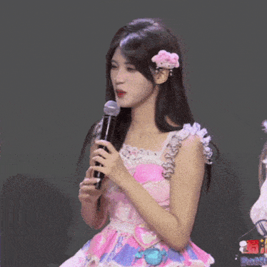 a girl in a pink dress is holding a microphone and giving the middle finger
