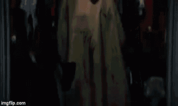 a man in a suit and tie is wearing a mask and holding a knife .