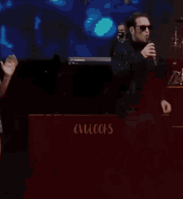 a man singing into a microphone in front of a keyboard that says cvlcops