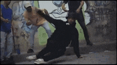 a group of men are standing around a man doing a handstand on the ground .