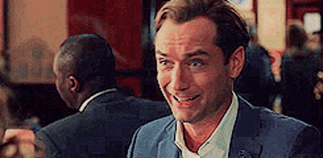 a man in a suit and tie is smiling while sitting in a restaurant .