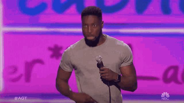 a man is holding a microphone in front of a purple background that says agt