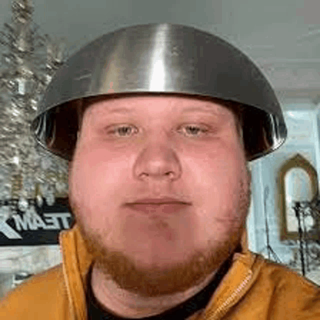 a man with a beard is wearing a metal bowl helmet .