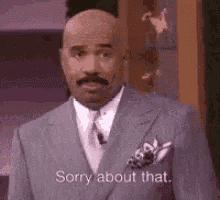 a bald man in a suit and tie is standing in front of a microphone and saying `` sorry about that '' .