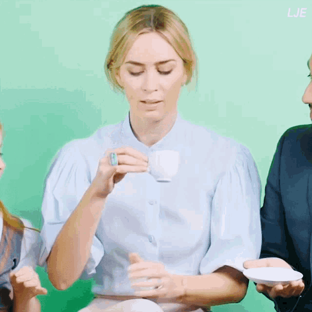 a woman in a blue shirt is holding a cup of coffee