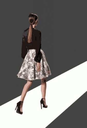 a woman wearing a black top and a white skirt is walking down a runway
