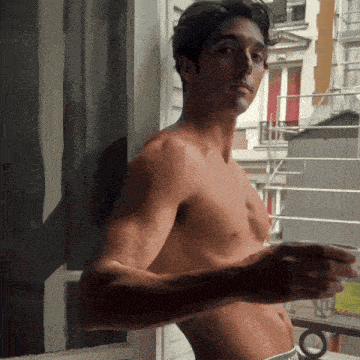 a shirtless man is leaning against a window sill
