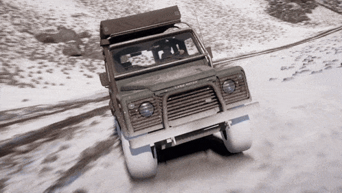 a land rover is driving through the snow on a road