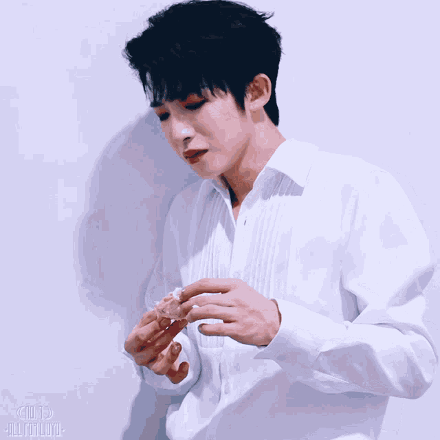 a man in a white shirt is eating a piece of food with a blue background that says ' all for you ' on it