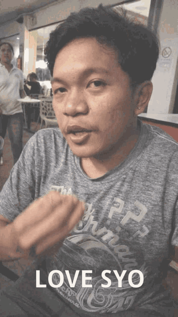 a man wearing a grey shirt that says lovesyo on it