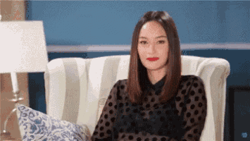 a woman is sitting in a chair wearing a black polka dot shirt